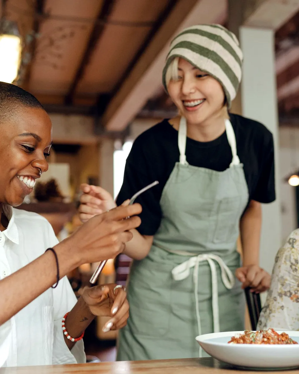 Two women laughing over food at a café table