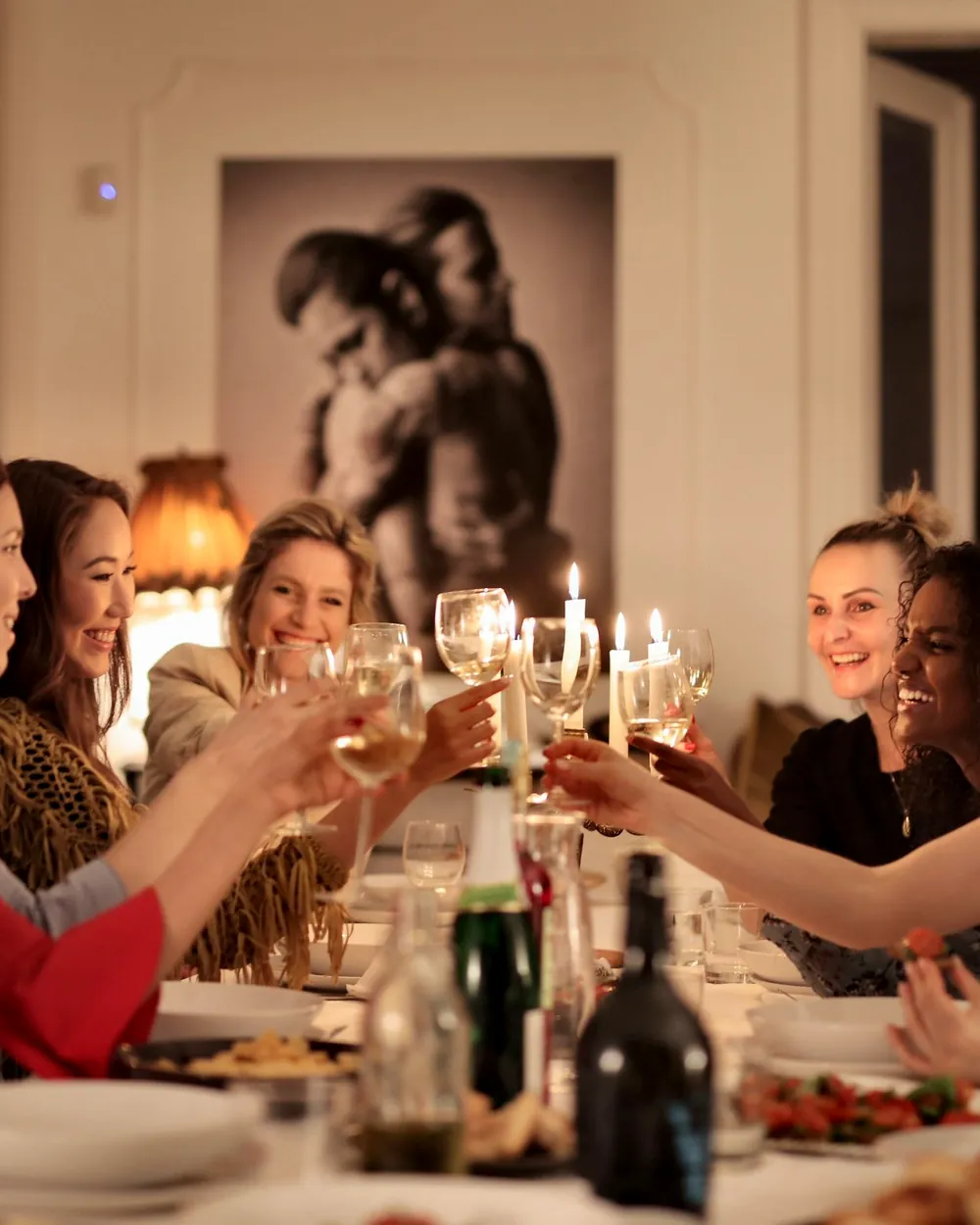 A group at a long table raising their glasses by candlelight