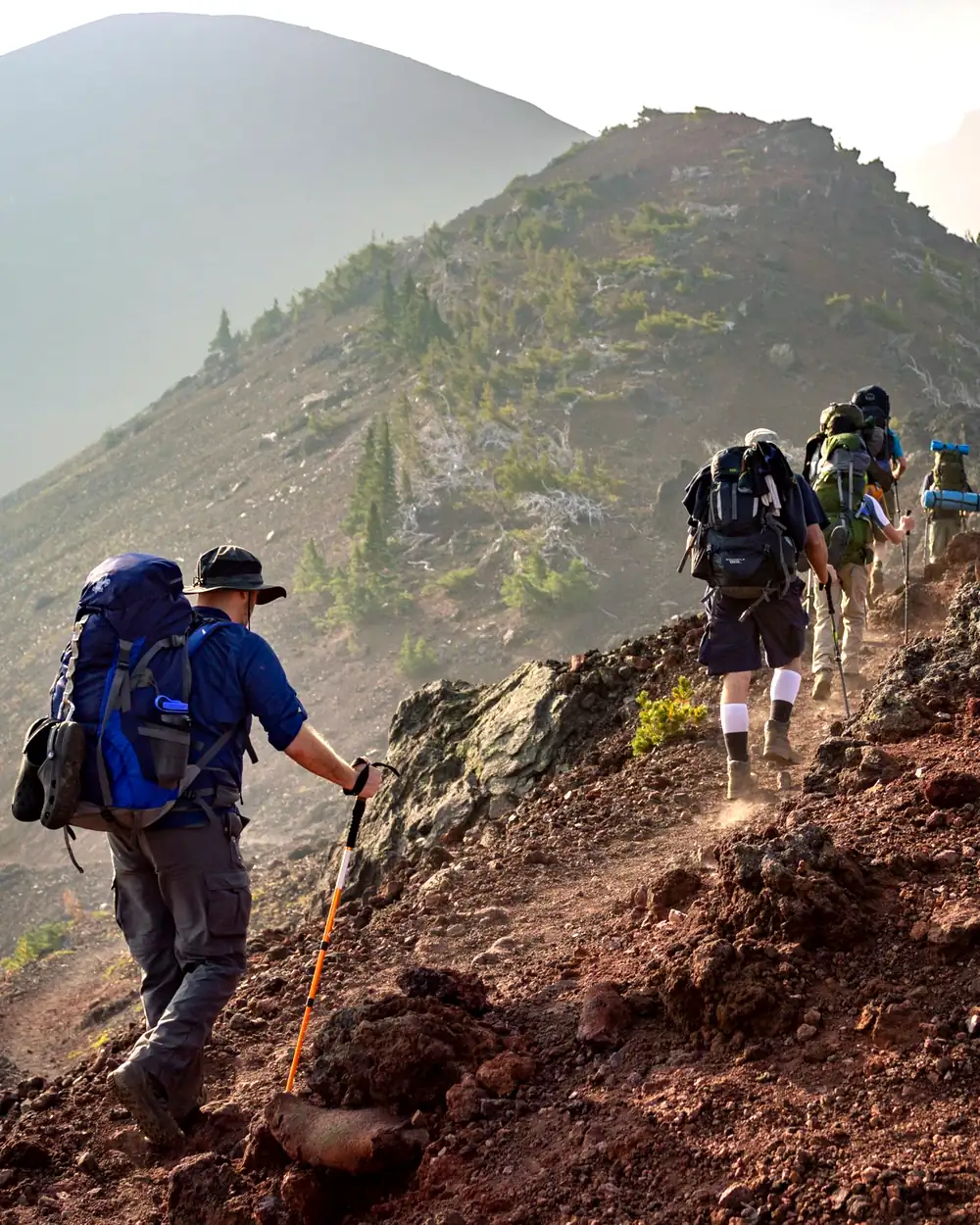 A group with backpacks climbing a mountain trail